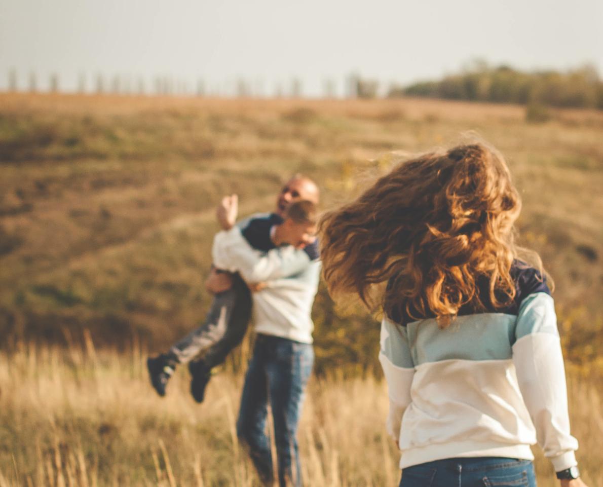 Mama en papa die samen met hun zoon aan het spelen zijn in een veld. 